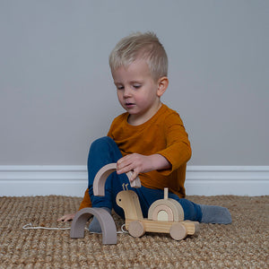 Wooden pull-along snail toy with stackable rainbow in muted colours.