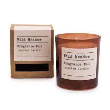 An amber coloured glass pot filled with a wax candle with Wild meadow aroma