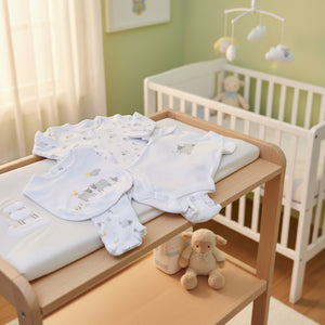 Baby sheep clothing set with onesies, a bib, and pants on a light beige background