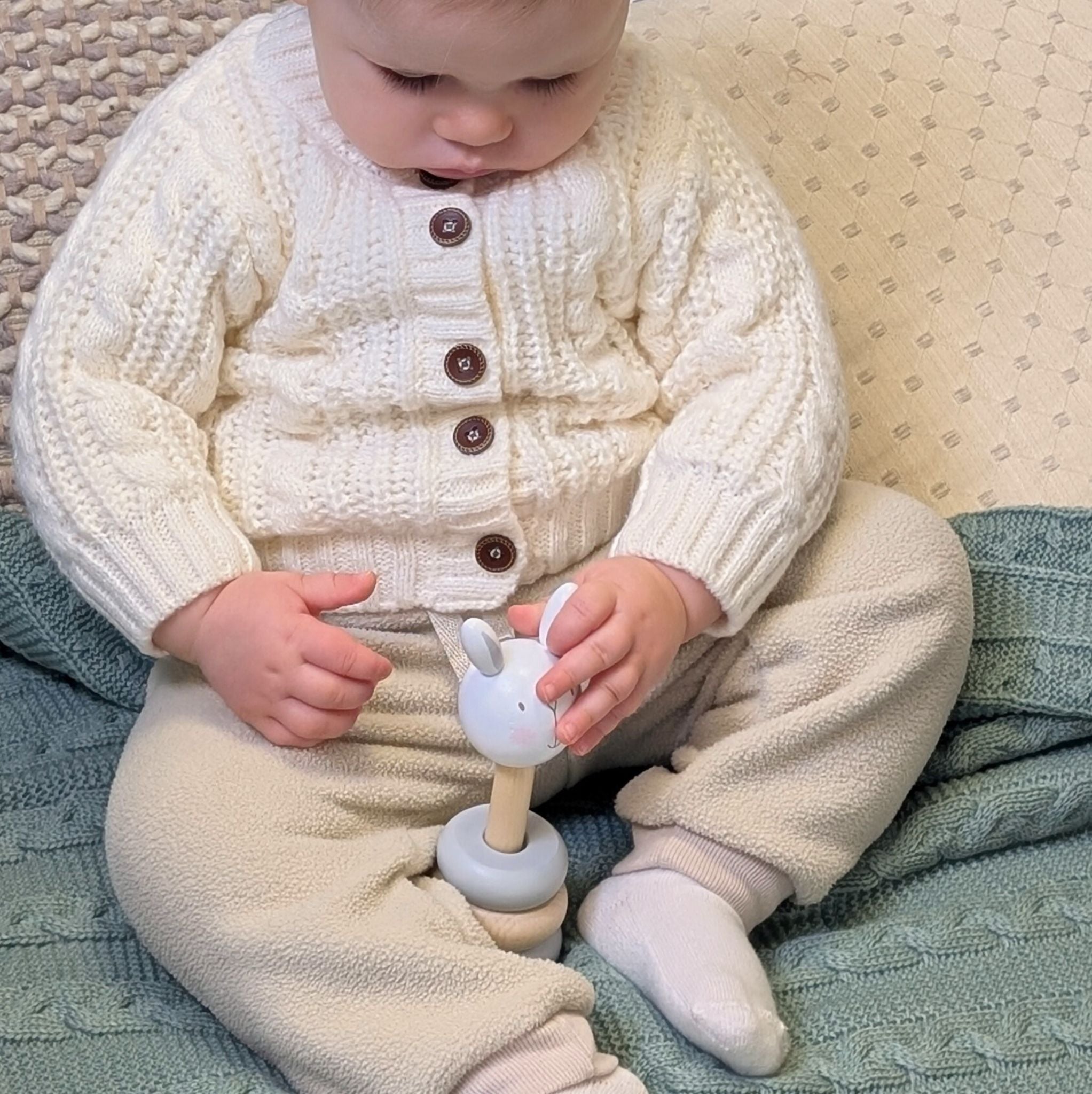 Wooden stacking rings tower game, with a baby putting the rabbit topper on.