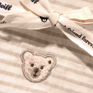 Close-up of the striped cotton burp cloth showing embroidered teddy bear detail and a tied ribbon.