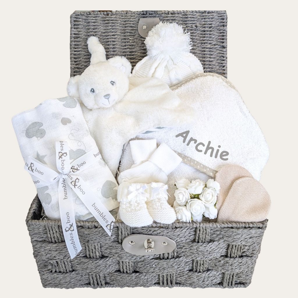 A baby hamper basket full of beautiful and white new baby gifts. Designed by Bumbles and Boo.