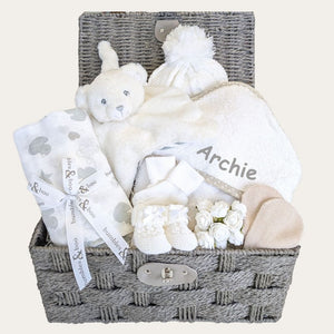 A baby hamper basket full of beautiful and white new baby gifts. Designed by Bumbles and Boo.