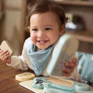 Baby holdng the wooden jigsaw pieces.