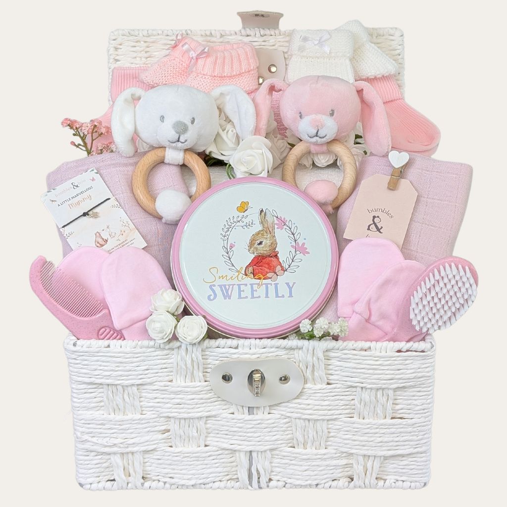 Twins gifts for girls in a white hamper basket. Includes biscuits and pink baby products.