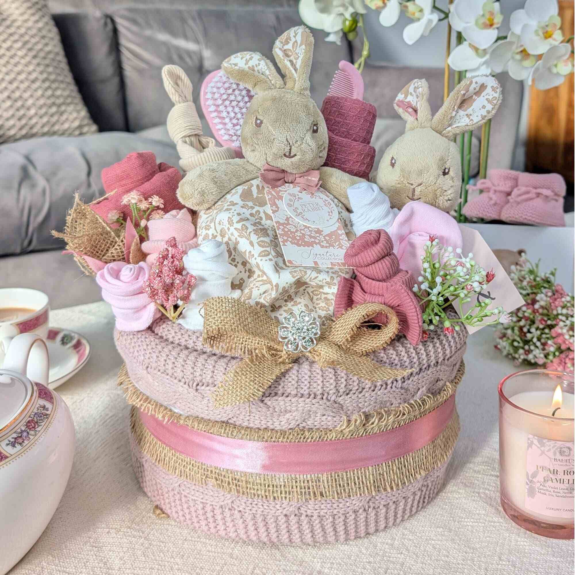 nappy cake for a new baby girl with a flopsy bunny theme. Dusky pink blanket and clothing. Bumbles and boo.