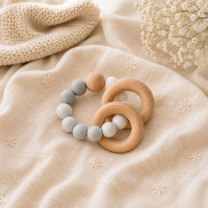 A wooden baby teether with grey & white silicone beaded ring.