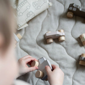 Toddler moving the wheel on a wooden toy car.