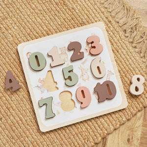 Wooden number board on a woven surface with coloured pieces 0–10 and two pieces shown beside it.