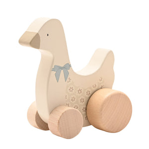 Angled view of a cream wooden goose showing its sage bow, floral body and four wooden wheels.