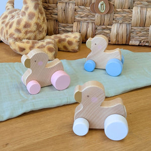 3 wooden toy push along ducks with pink, blue or white wheels