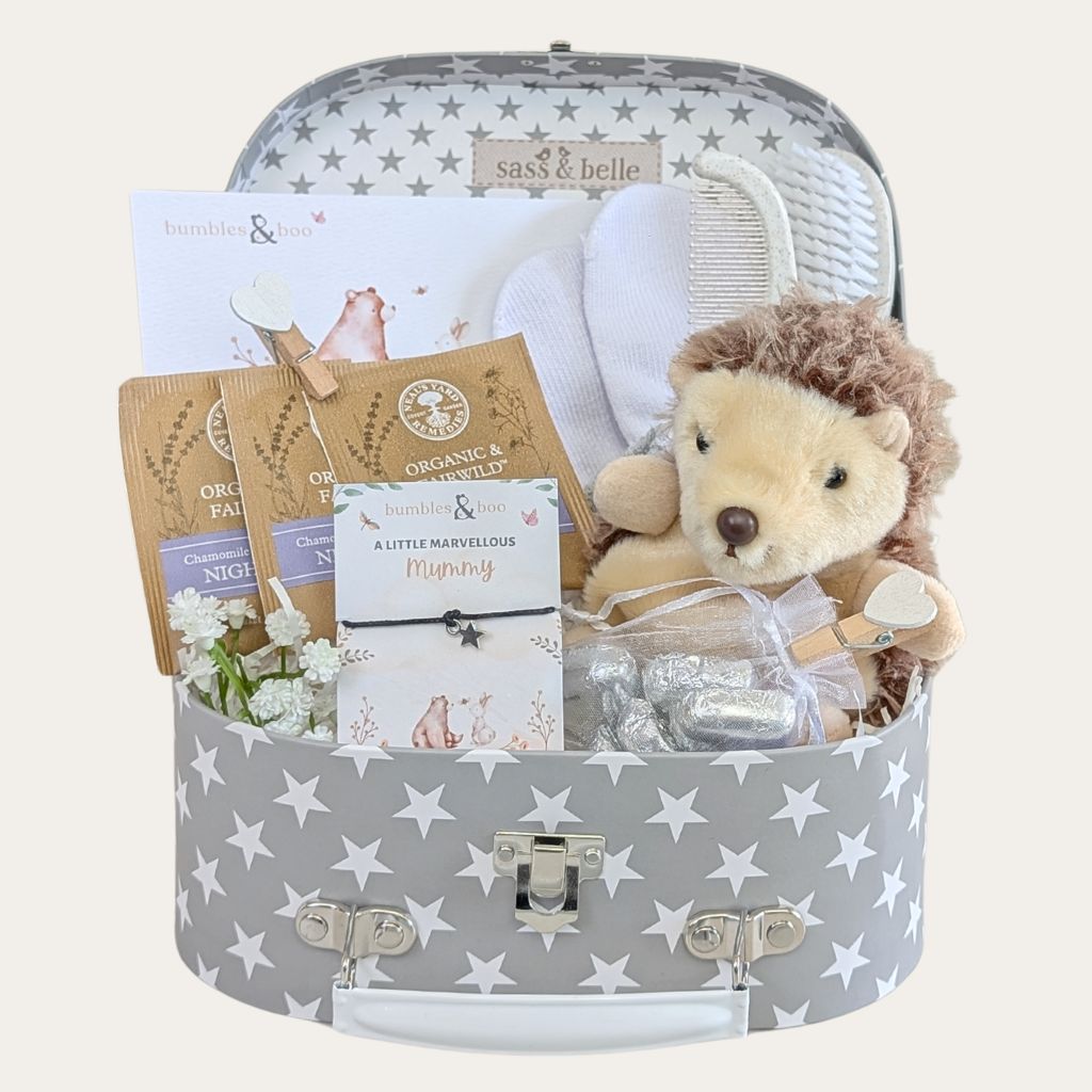 Affordable baby shower gift hamper with chocolates, tea, soft toy, baby mittens, brush set, and keepsake trunk.