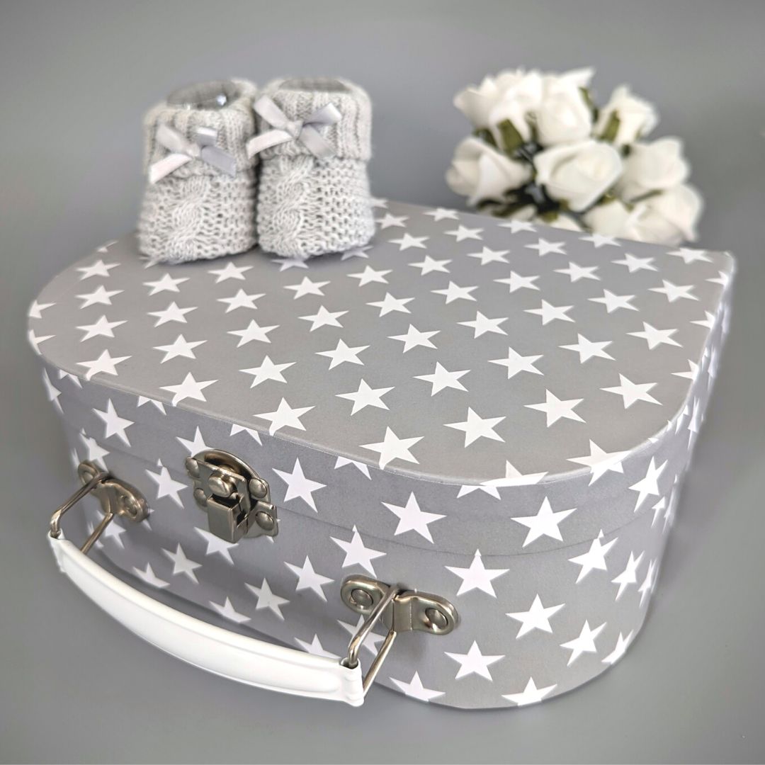 Grey with white stars luggage trunk and white baby booties.