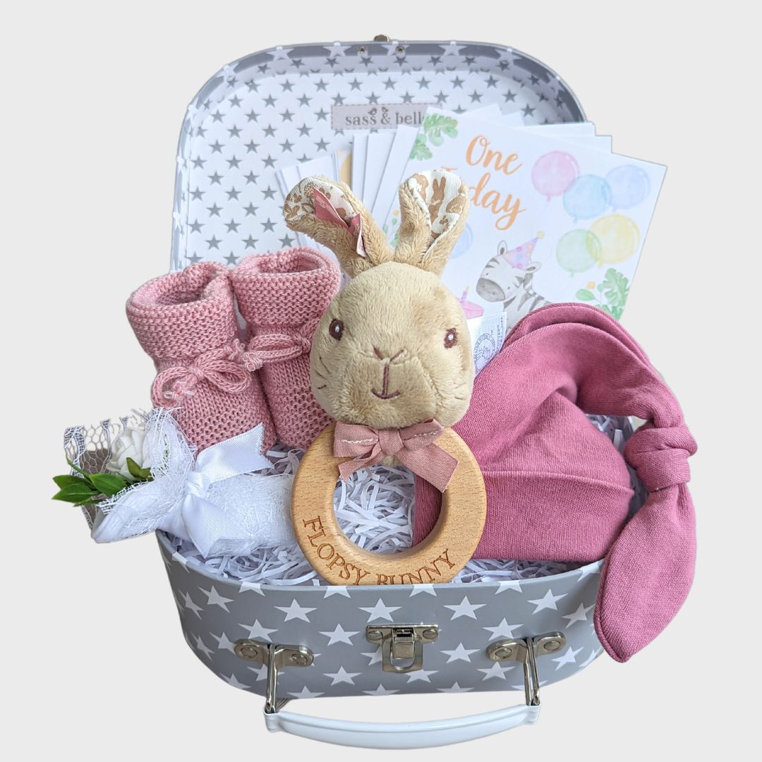 Baby girl gifts hamper trunk with flopsy bunny theme. Small grey stars suitcase with darlk pink hat &amp; booties