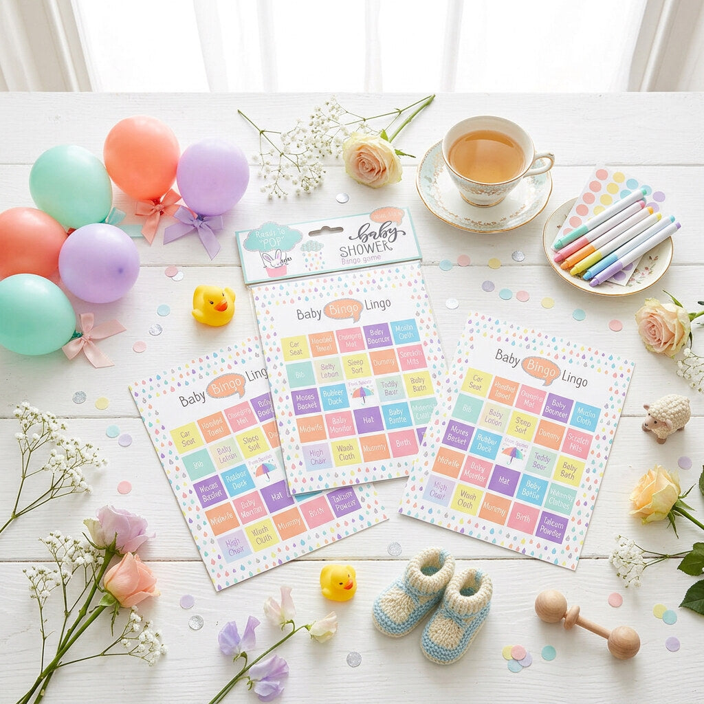 Baby shower bingo cards with pastel word grids displayed beside balloons and coloured pens.
