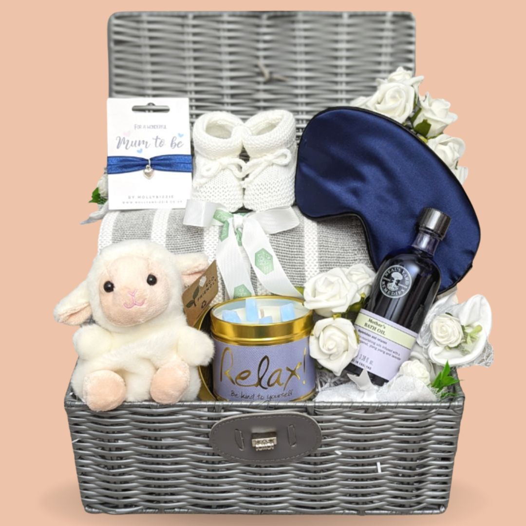 Baby shower gifts hamper in a brown wicker basket. Blue, white and grey colour theme.