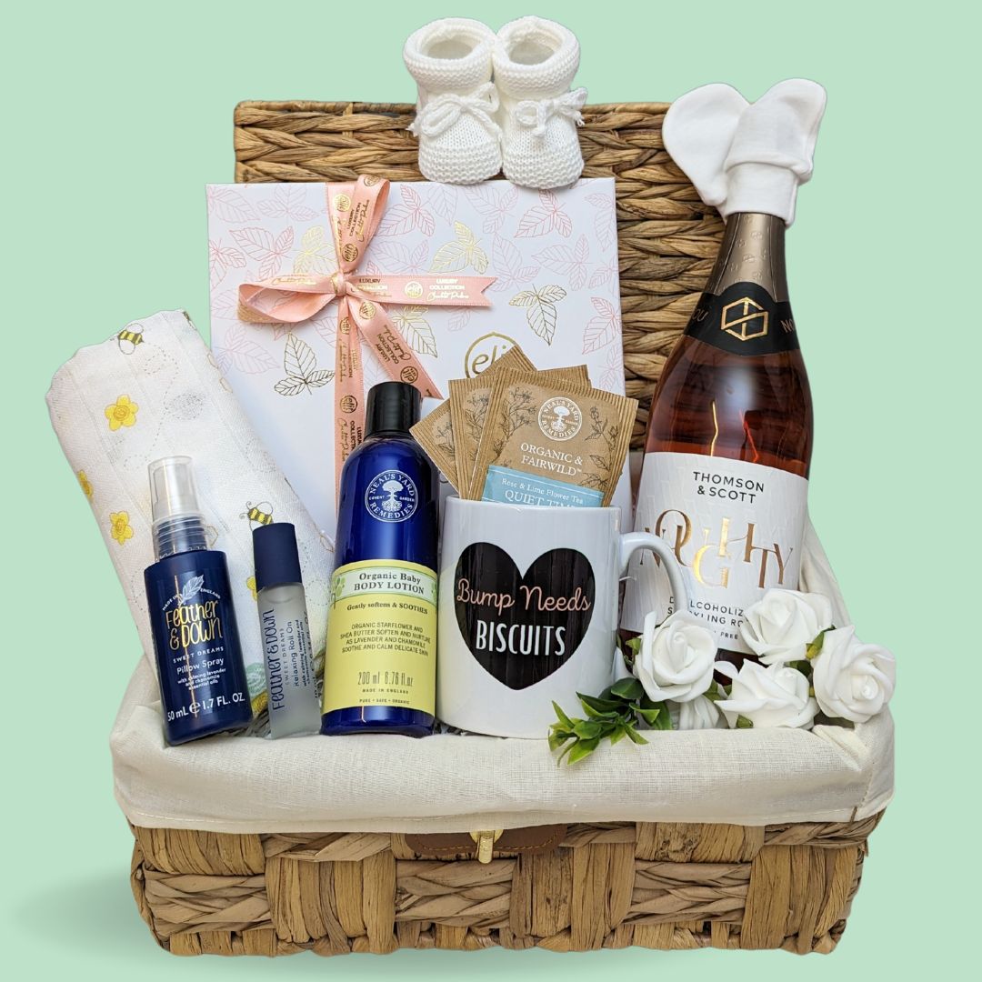 Baby shower gifts hamper with treats for mum to be and baby. Includes chocolates and organic skincare packed in a basket.