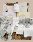 new mum gifts hamper with 2 Neal's Yard gift boxes, white baby clothes, and soft toys. Topped with a 'just arrived' hat.