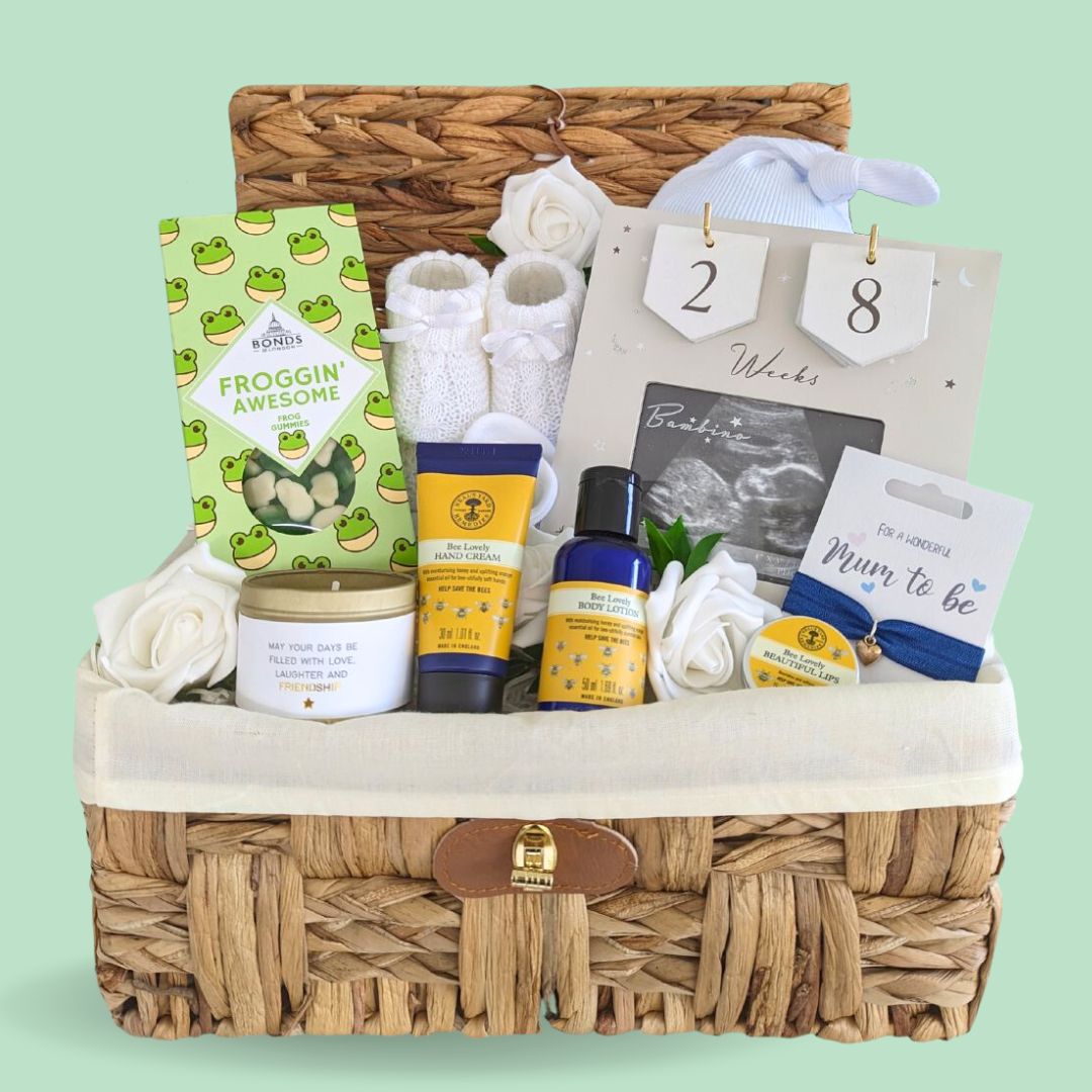 Mum to be hamper with gifts including countdown frame, sweets, pamper skincare,& candle in a basket.