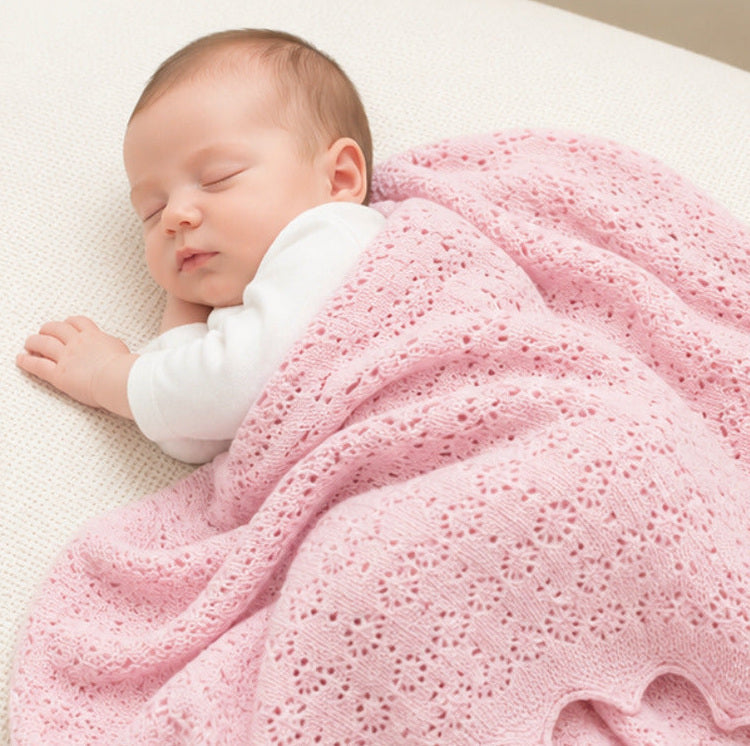 Pink cashmere baby blanket. This shawl has a delicate pointelle openwork pattern and is covering a sleeping newborn baby
