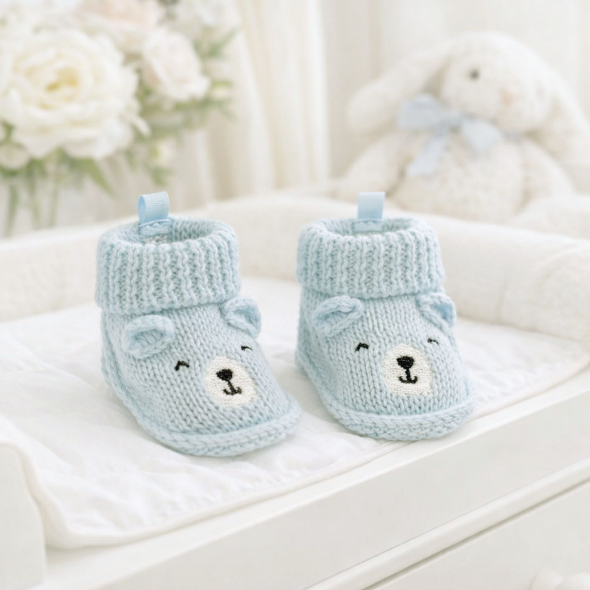 Knitted baby booties with blue bear face embroidery and ears in a sky blue, suitable for newborn babies.