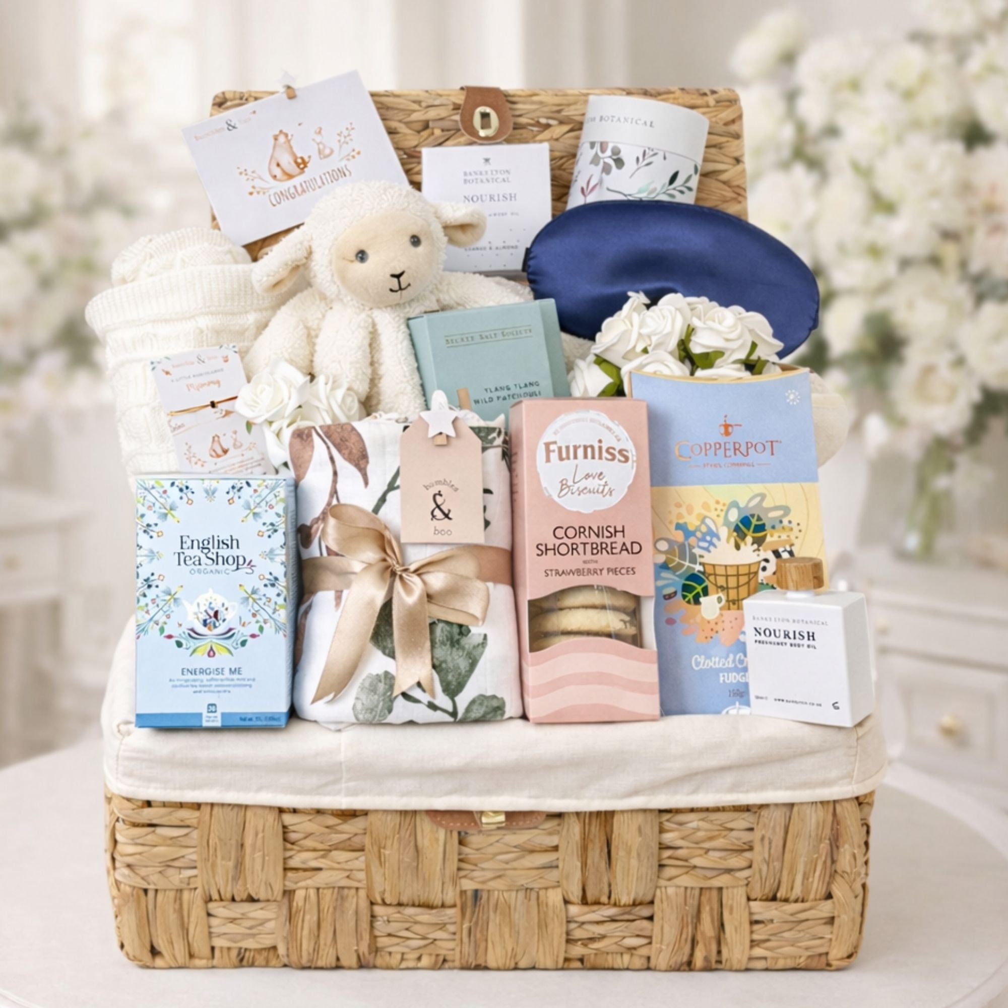 Large mum to be hamper packed with pregnancy gifts presented in a wicker basket with white lamb comforter and sweet treats for mum to be from Bumbles and Boo. 