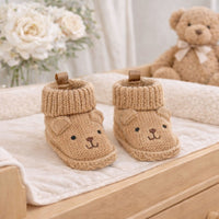 Knitted baby booties with beige bear face embroidery and ears in a soft neutral brown colour, suitable for newborn babies.