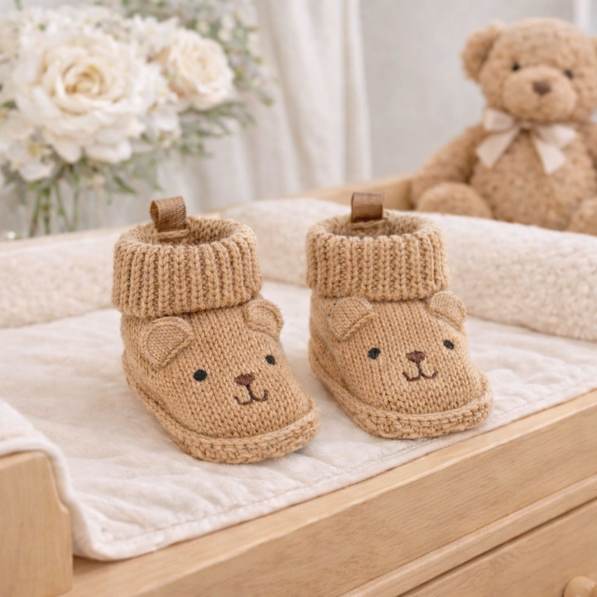 Knitted baby booties with beige bear face embroidery and ears in a soft neutral brown colour, suitable for newborn babies.