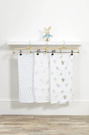 Three baby blankets with different patterns hanging on a rack against a white wall.