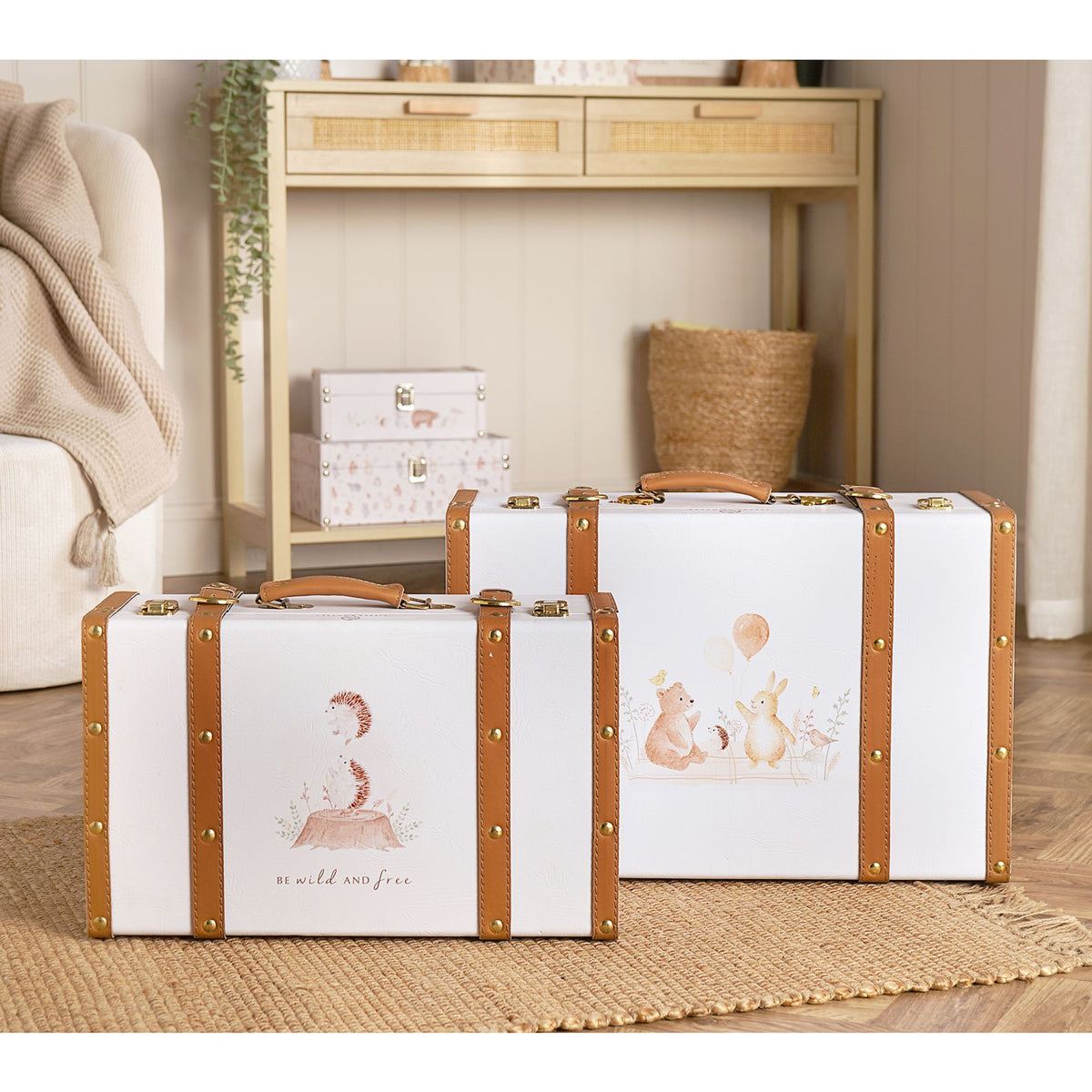 Two illustrated animal suitcase storage boxes with brown straps displayed on a nursery rug.