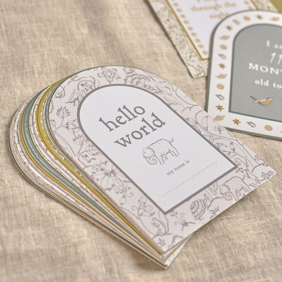 Stack of arched milestone cards topped by hello world on a wooden surface