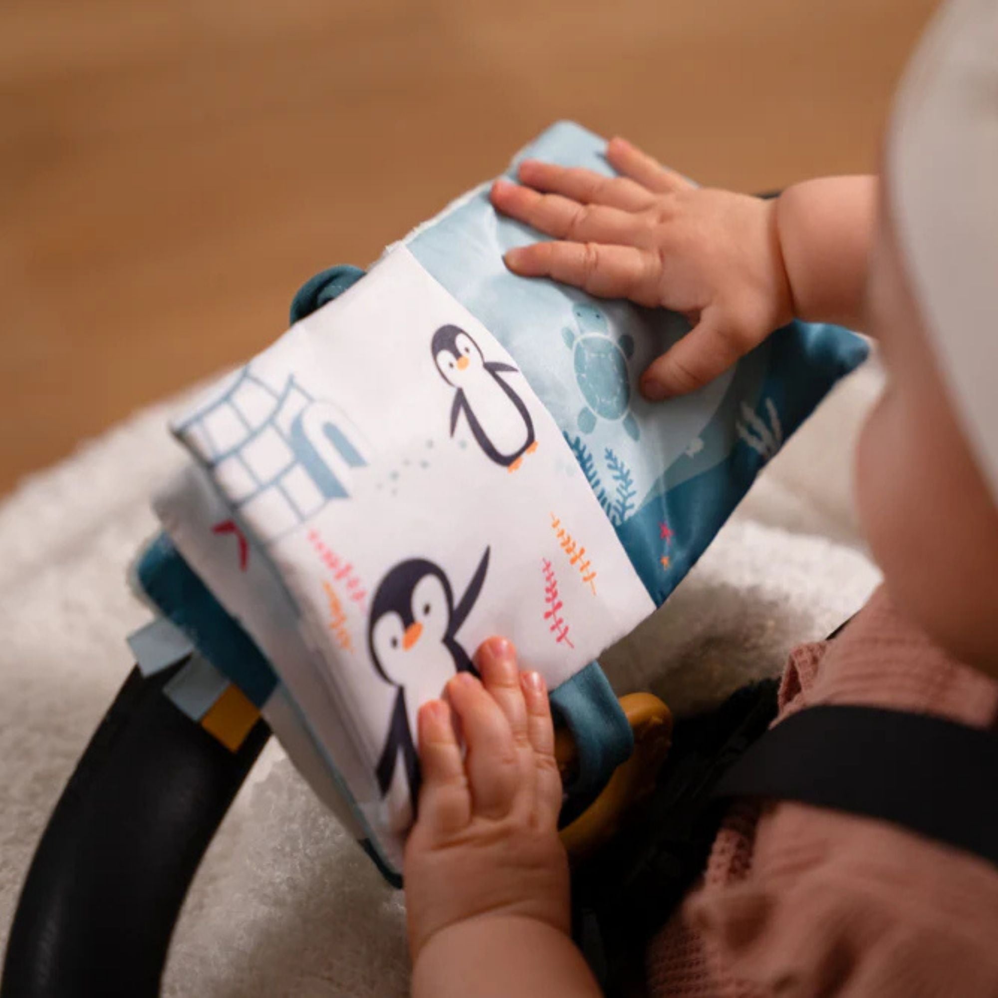 Soft ocean themed baby activity book with sensory pages, open on the penguin page