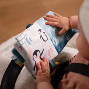 Soft ocean themed baby activity book with sensory pages, open on the penguin page