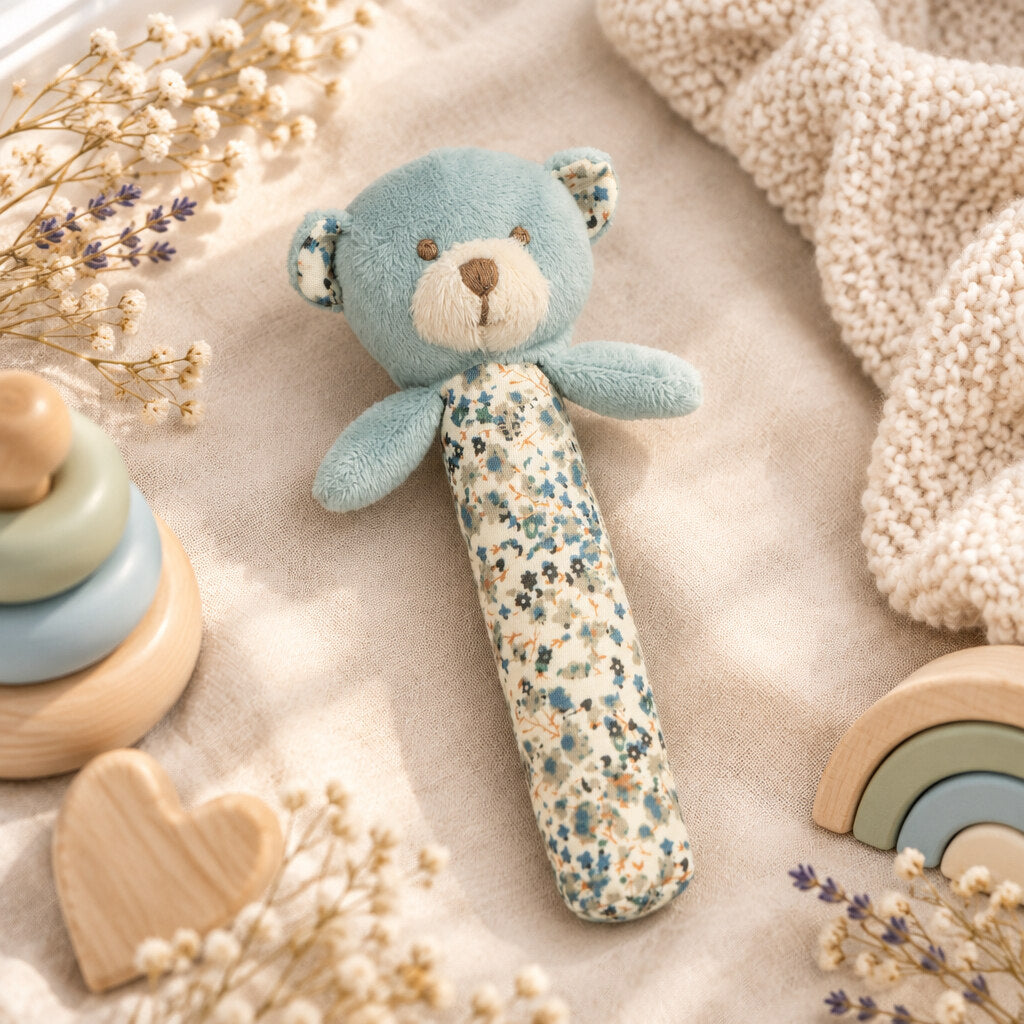 Blue Barney Bear stick rattle with a cream floral-print handle on beige fabric, from the baby toys range.