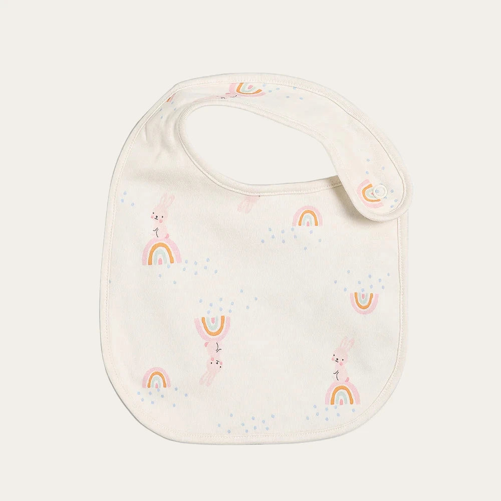 Cream baby bib with rainbow print and snap fastening