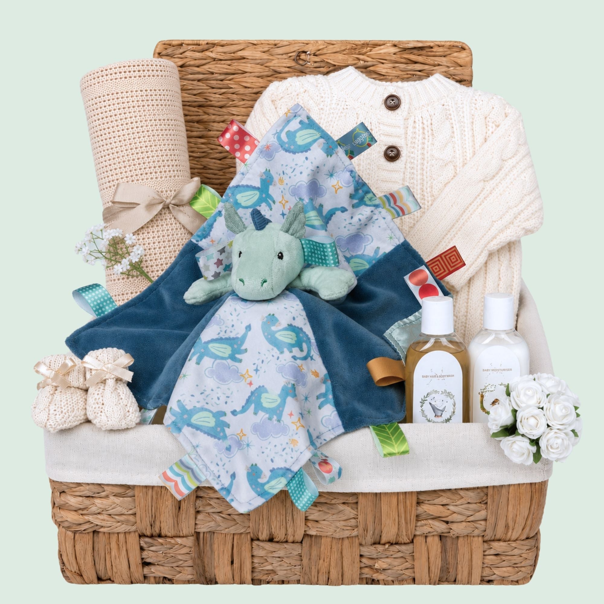 A present for a new baby boy with a cream knitted cardigan and giraffe soft toy in a hamper basket.