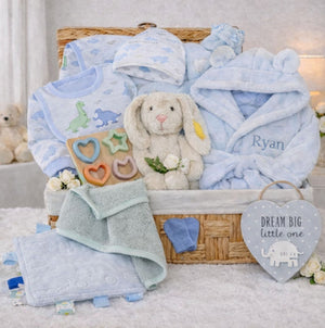 Baby boy gift basket with dinosaur clothing and blue hooded dressing gown in a hamper.
