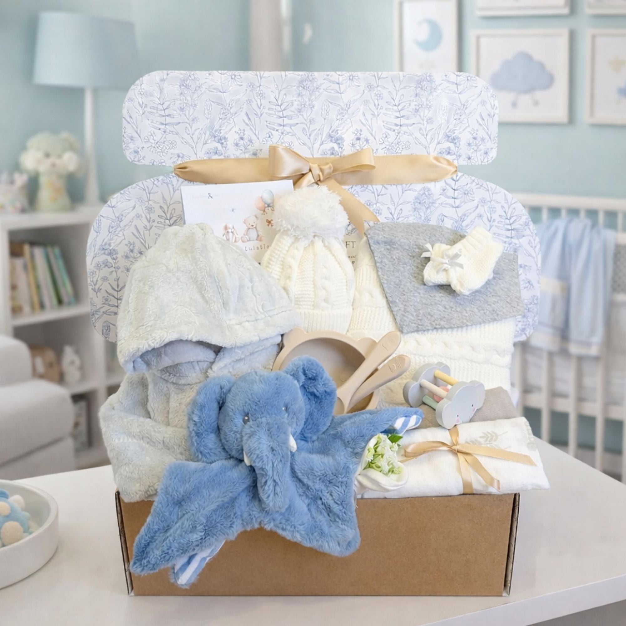 Gifts hamper for a baby boy with a knit hat and blanket set presents and blue elephant comforter soft toy.