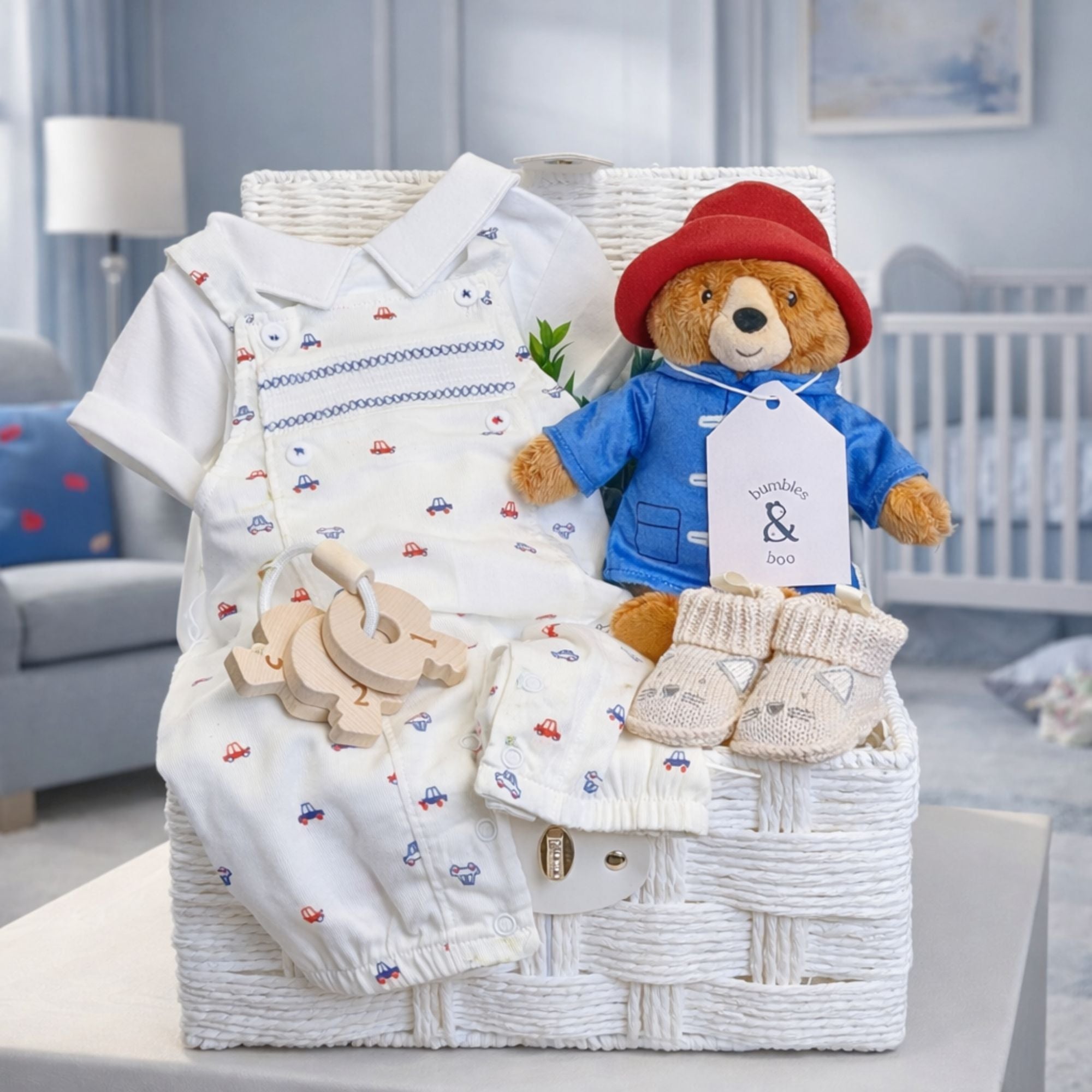 White baby boy hamper with gifts including Paddington bear soft toy and baby outfit set in blue and red