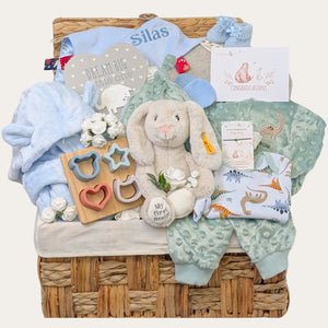 Large baby boy gifts hamper with cotton dinosaur clothing set and Steiff bunny in a hamper basket.