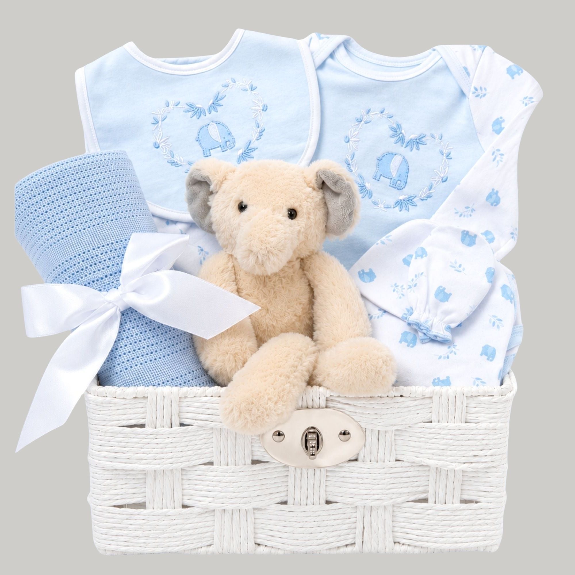 New baby boy gifts in a white hamper basket with blue baby clothes, elephant toy and cellular blanket