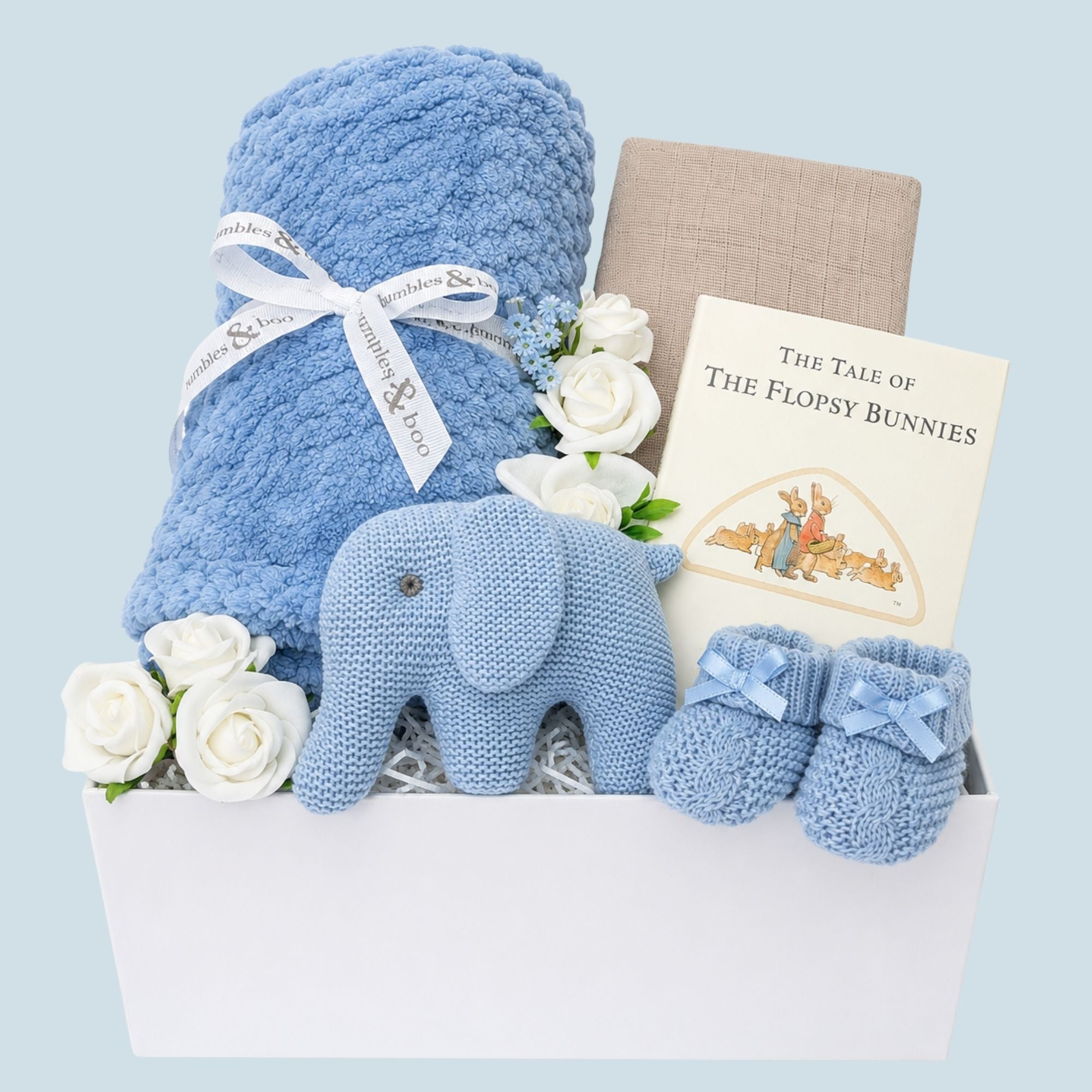 Baby boy gifts in a box with dusky blue blanket and blue elephant rattle. Hamper designed by Bumbles and Boo.