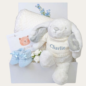 White plush bunny with 'Charlie' on a white background, surrounded by baby items.