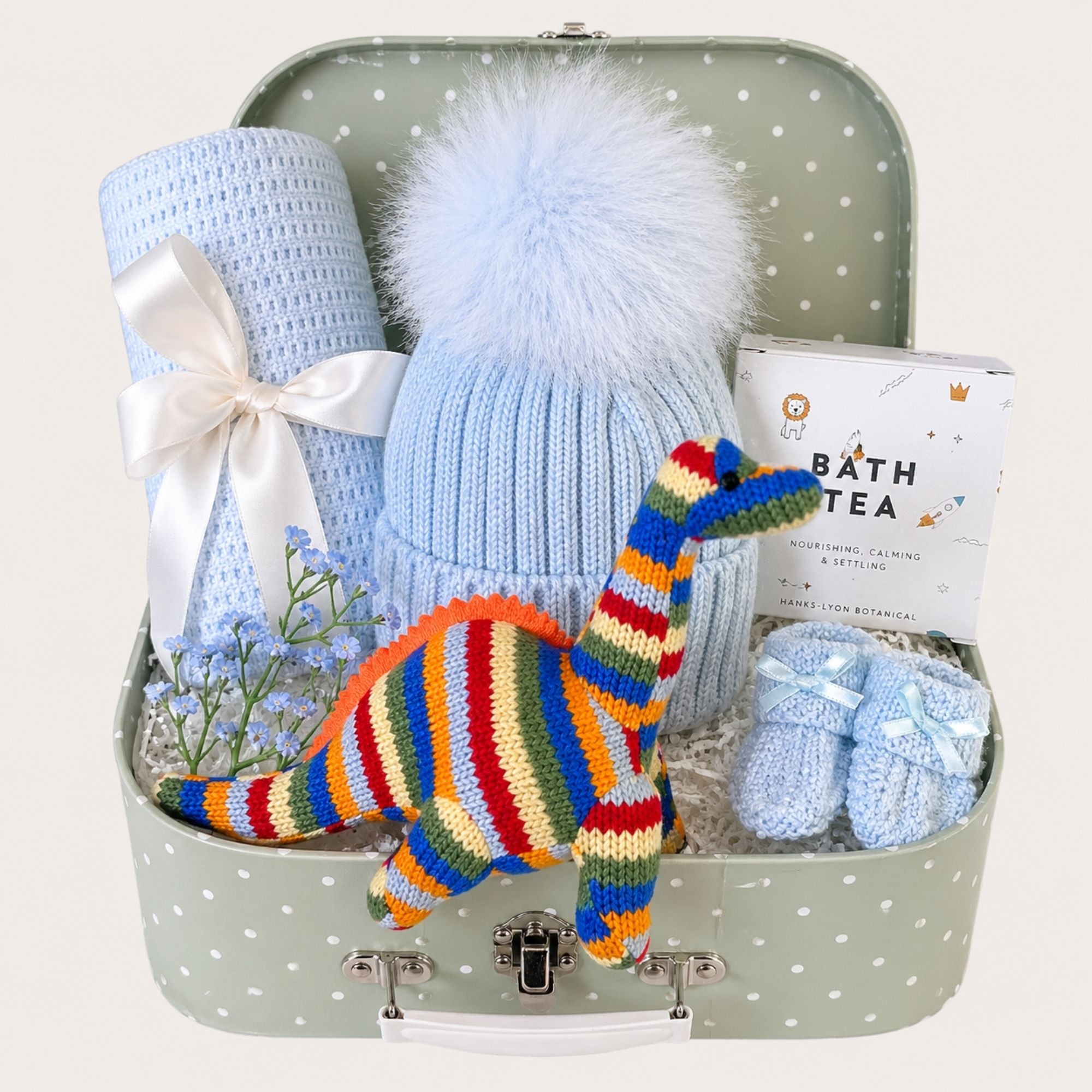 Baby boy hamper packed with gifts including blue clothes and stripy dinosaur.