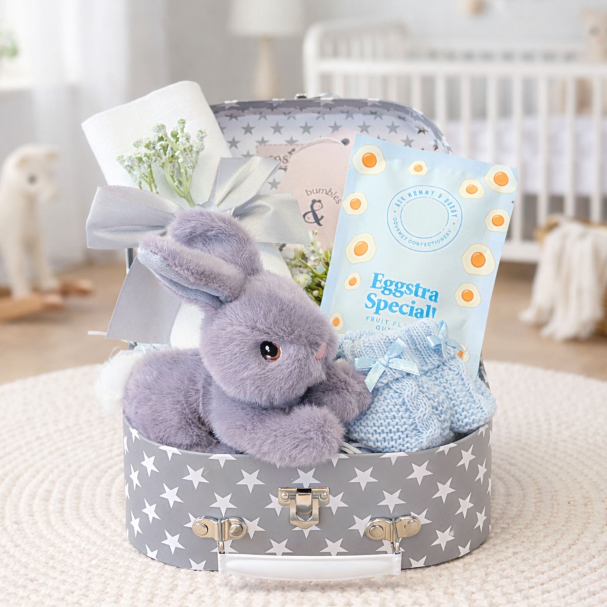 Small baby boy gifts hamper with gifts including a grey rabbit soft toy and sweet treats.
