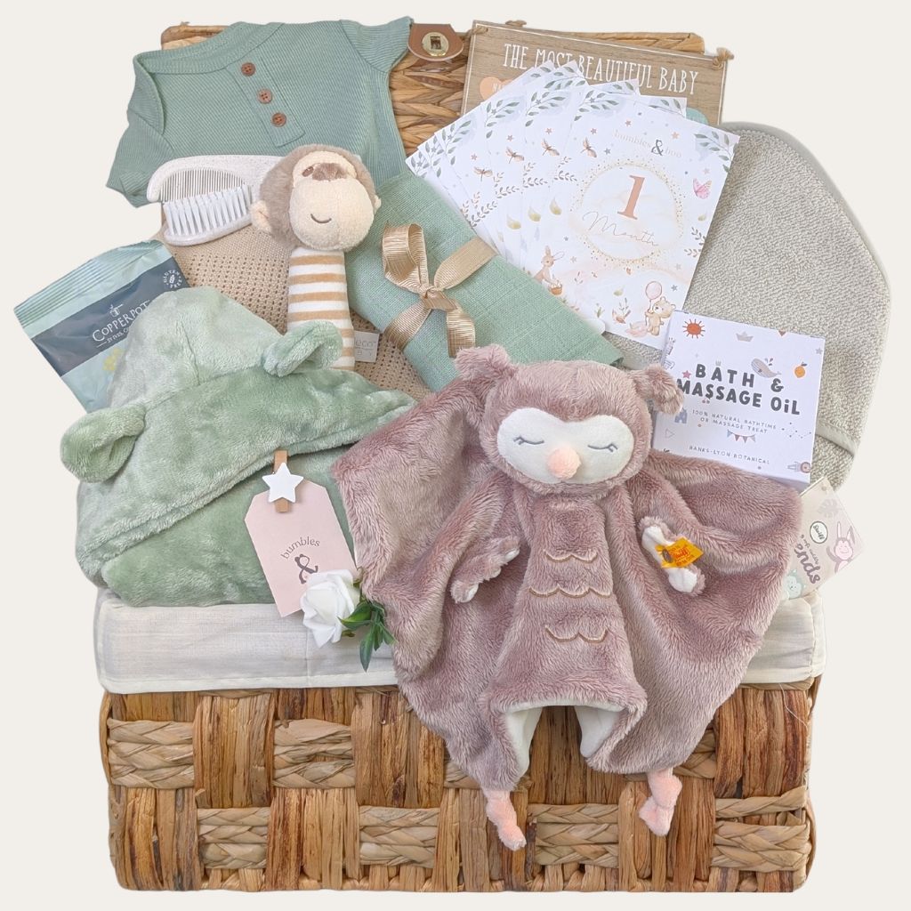 Luxury newborn baby boy gifts hamper featuring a Steiff owl comforter and olive green organic baby essentials in a wicker basket 