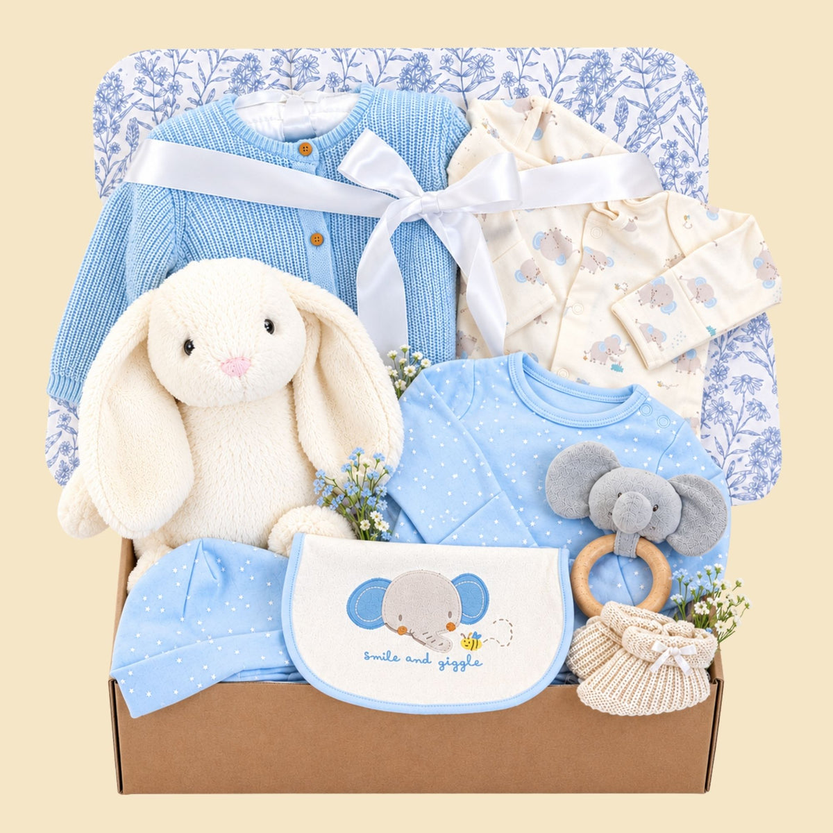 New baby boy gift hamper box with blue and white gifts. This hamper contains a bunny soft toy and blue elephant clothes set.