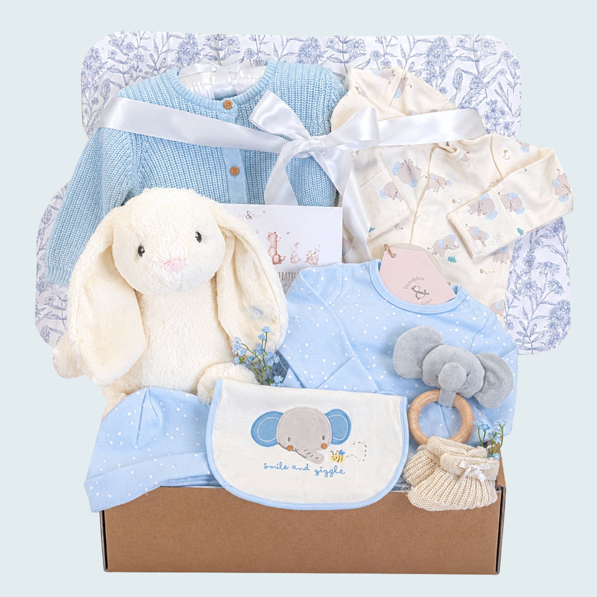 New baby boy gift hamper box with blue and white gifts. This hamper contains a bunny soft toy and blue elephant clothes set.