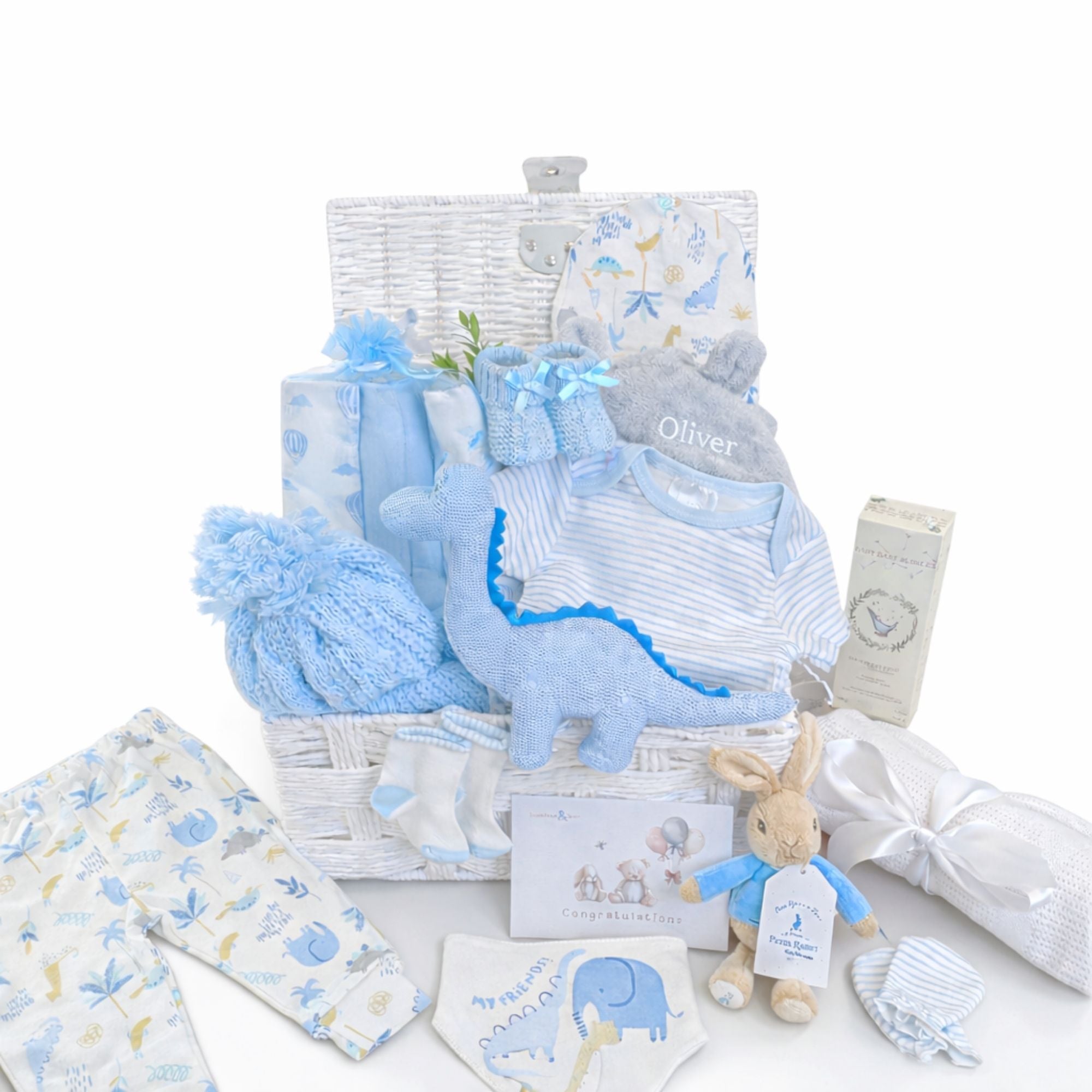 Baby boy gifts set with dinosaur clothing and organic skincare baby boy presents in a white basket.