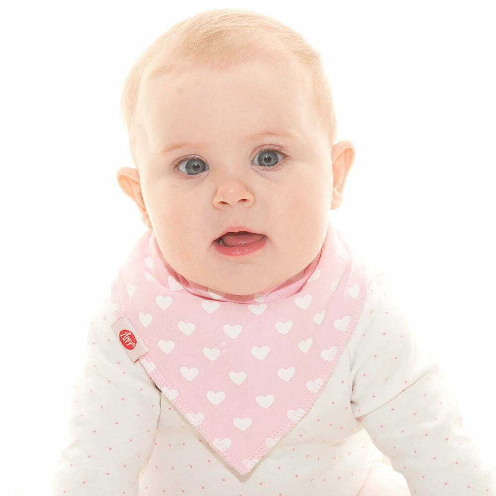Baby wearing a pink bib with white heart patterns on a white background
